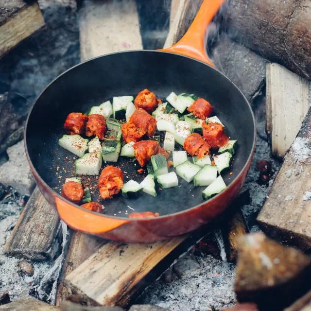 Vegetables cooking in a pan over a campfire