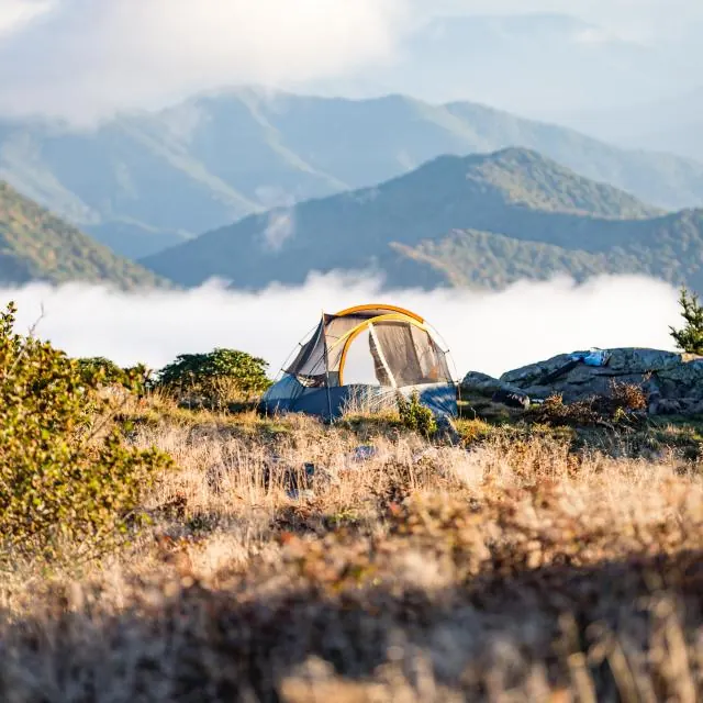 A tent pitched on a hillside above the clouds